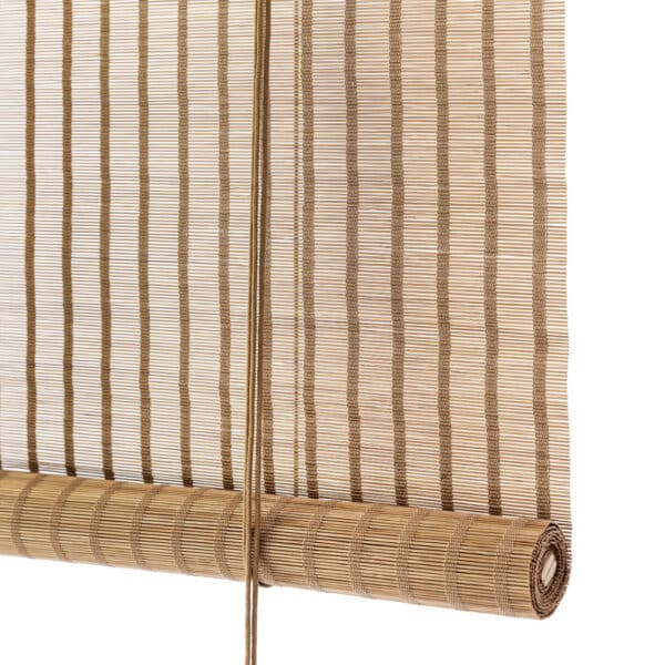 Natural bamboo window blind partially unrolled with vertical slats and hanging cords to the front.